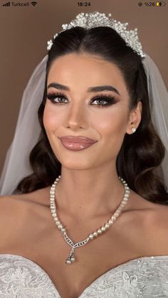 a woman in a wedding dress wearing a necklace and tiara with pearls on it