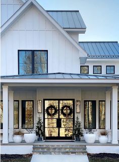 a white house with a black front door and wreaths on the front entrance steps