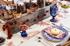 the table is set with plates, silverware and candles for an autumn themed dinner