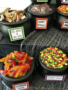 halloween candies and candy in black containers on display at a party or event with signs