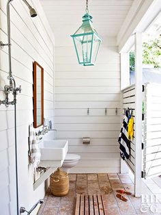 a white bathroom with wood flooring and a lantern hanging from the ceiling above it