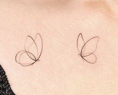 two small butterfly tattoos on the back of a woman's chest