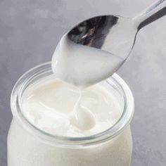 a spoon full of milk being poured into a jar