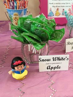 snow white's apple candy is displayed in a glass vase on a pink tablecloth