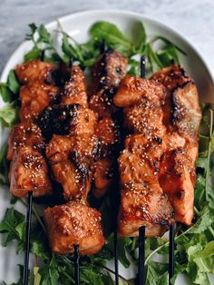 grilled salmon skewers on a plate with greens