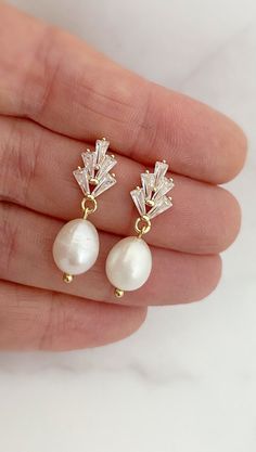 a pair of earrings with white pearls and crystal leaves on the front, set in yellow gold