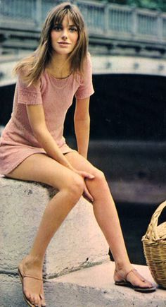 a young woman sitting on top of a cement wall next to a wicker basket