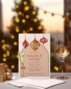 a table topped with two wine glasses next to a greeting card and christmas ornament