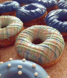 there are many donuts with icing on the table and one has blue frosting