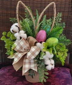 a basket filled with cotton and greenery sitting on top of a purple chair next to a pillow