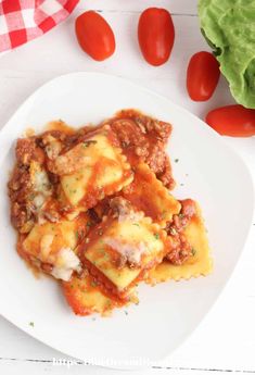 a white plate topped with lasagna covered in sauce and cheese next to lettuce