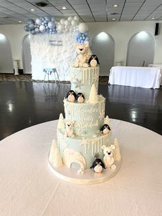 a three tiered cake with penguins on top