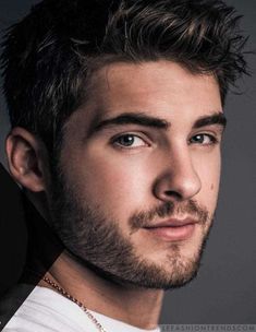 a close up of a person with a beard and wearing a white t - shirt