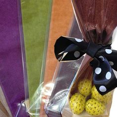 four different colored bags with polka dots on them and one has a black ribbon tied around it