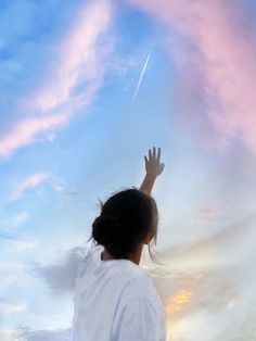 a person reaching up into the sky to catch a frisbee with their hand