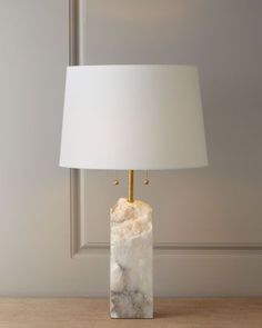 a lamp that is sitting on top of a wooden table in front of a wall