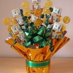 a gold vase filled with lots of money and wrapped in green ribbon on top of a wooden table