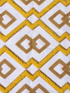 a close up view of a yellow and white fabric with geometric design on the side