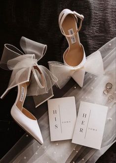 two pairs of shoes with bows on them sitting next to a card and ring box