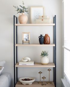 a shelf with vases and other items on top of it in a living room