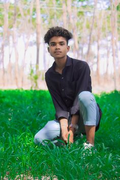 a young man kneeling down in the grass