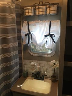 a bathroom with a sink, shower curtain and toilet paper roll on the shelf above it