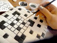 a person cutting into a cake with black and white squares on it