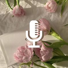 a bouquet of pink flowers sitting next to a microphone on top of a white sheet