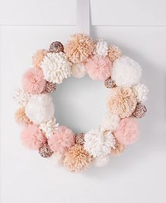 a pink and white pom - pom wreath hanging on a wall next to a clock