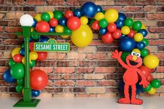 the sesame street sign and balloon arch in front of a brick wall with colorful balloons