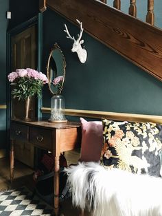 a table with flowers and a deer head on it in front of a stair case