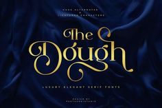 the dough luxury elegant serif font with gold lettering on a blue satin fabric background