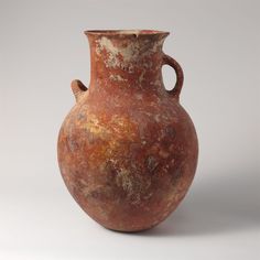 an old brown vase is sitting on a white surface with no one around it,