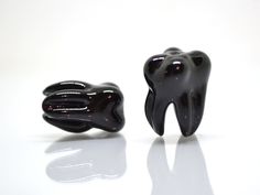 two black tooth shaped objects on a white surface