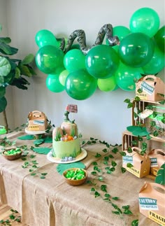 a table topped with lots of green balloons and cake on top of a wooden table