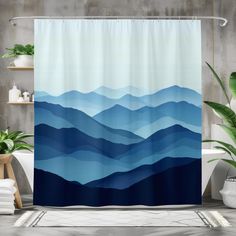 a bathroom with a shower curtain that has blue mountains on it and plants in the background