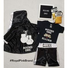 a black boxing outfit with white lettering on the chest and two matching shorts are next to each other