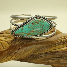 Royston Turquoise Cuff Bracelet, Genuine Turquoise Cabochon, Sterling Silver Bracelet, Flower Concho This cuff bracelet is a statement piece to wear! Big Blue Green, authentic Royston Turquoise Cabochon from Nevada. Beautiful Turquoise encased Fine and Sterling Silver. I hand picked this freeform shape cabochon because of its beautiful blue green colors knowing it would make a statement bracelet. The Turquoise Cab is bezel set with a hand sawn serrated bezel edge. I soldered a sterling silver be Southwestern Turquoise Gemstone Bracelets, Southwestern Turquoise Gemstone Bracelet, Adjustable Turquoise Cuff Bracelet With Natural Stones, Turquoise Gemstone Bracelet In Southwestern Style, Turquoise Natural Stone Cuff Bangle, Turquoise Bangle Cuff Bracelet With Natural Stones, Adjustable Turquoise Bangle With Oyster Bracelet, Bohemian Turquoise Nickel-free Cuff Bracelet, Adjustable Turquoise Cabochon Bracelet