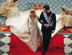 a man and woman in wedding attire standing next to each other on a red carpet