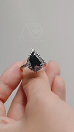 a person is holding an engagement ring with a black diamond in it's center