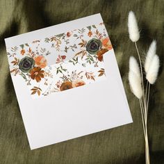 an open card with flowers and leaves on it next to some pamodia stalks