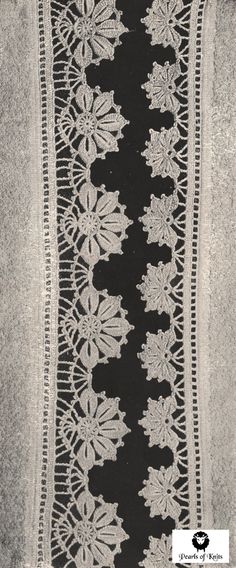 a black and white photo of an intricate lace border with flowers on the edge,