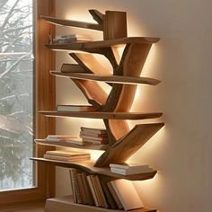 a wooden book shelf with books on it in front of a window and snow covered trees outside