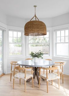 a dining room table with four chairs and a basket hanging from the ceiling over it