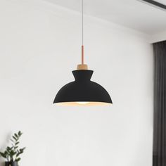 a black lamp hanging from the ceiling in a living room with white walls and curtains