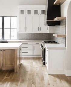 an empty kitchen with white cabinets and wood floors is pictured in this image from the front view