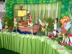 a party with tinkerbells on the table and green balloons in the background