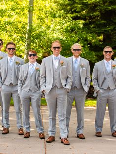 a group of men standing next to each other wearing suits and sunglasses with trees in the background