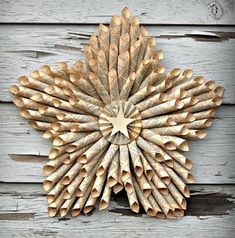 a wooden star shaped wreath hanging on the side of a wood wall, made out of rolled up paper