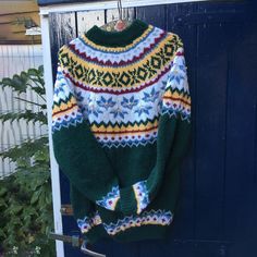 a green sweater hanging on a blue door